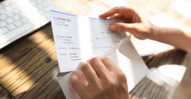 Businessperson Opening Envelope With Paycheck