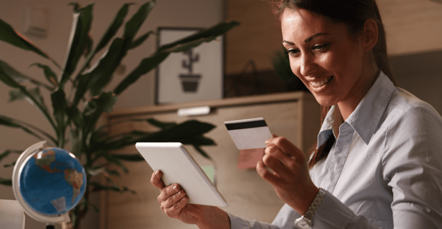 woman looking at credit card while holding tablet woman looking at credit card while holding tablet