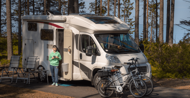 woman-standing-outside-of-RV-with-bikes-and-chairs Man hands using online banking and icon on tablet screen
